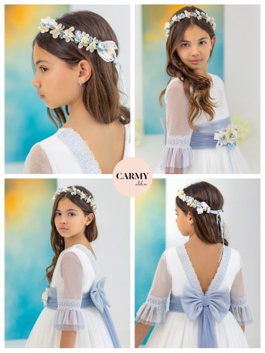 Niña con vestido blanco y cintillo de flores, mostrando su peinado y el lazo azul en la espalda.