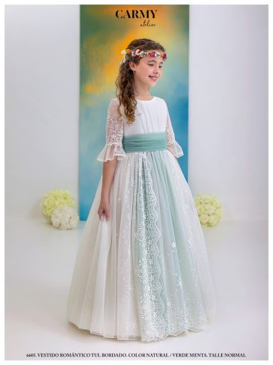 Niña en un vestido de fiesta blanco y verde, con flores en el cabello y fondo colorido.