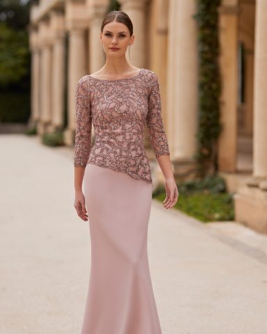 Mujer modelando un vestido largo rosa con detalles brillantes en la parte superior.