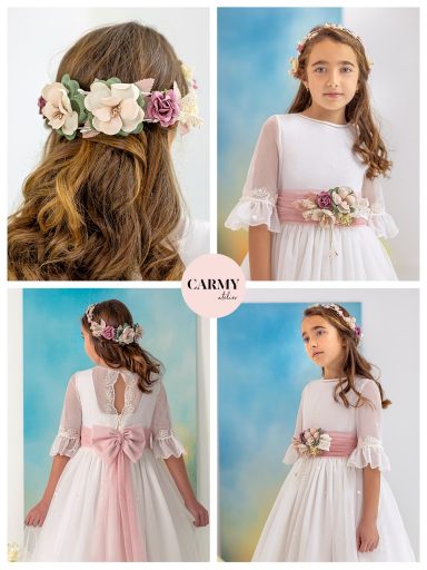 Niña con vestido blanco y cinturón rosa, llevando una corona de flores.