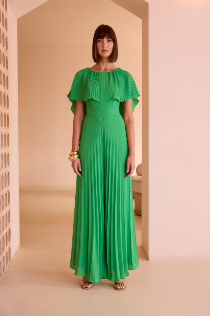 Modelo femenina viste un vestido largo verde en un entorno minimalista.