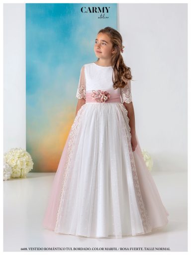 Niña con vestido blanco y rosa, de mangas cortas, posando frente a un fondo colorido.